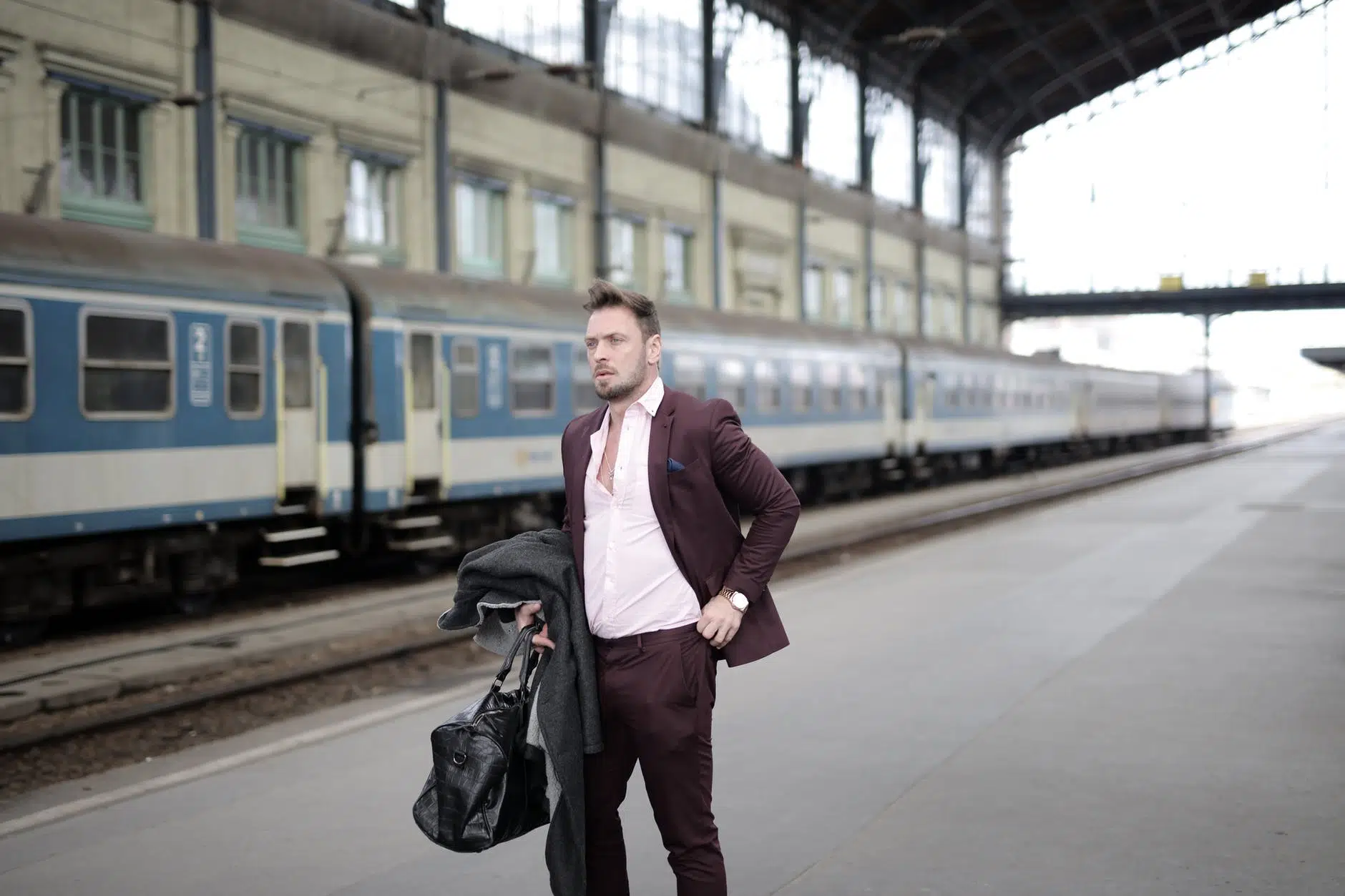 elegant businessman standing on platform and waiting for train on railway station